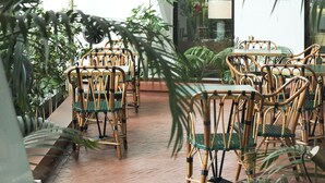 Un restaurante con mobiliario de mimbre y plantas en macetas.