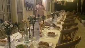 A long dining table set for a meal with chairs on both sides, decorated with flowers and bottles. - Superb 250 m2 Provencal farmhouse for rent (Mas-Blanc-des-Alpilles)