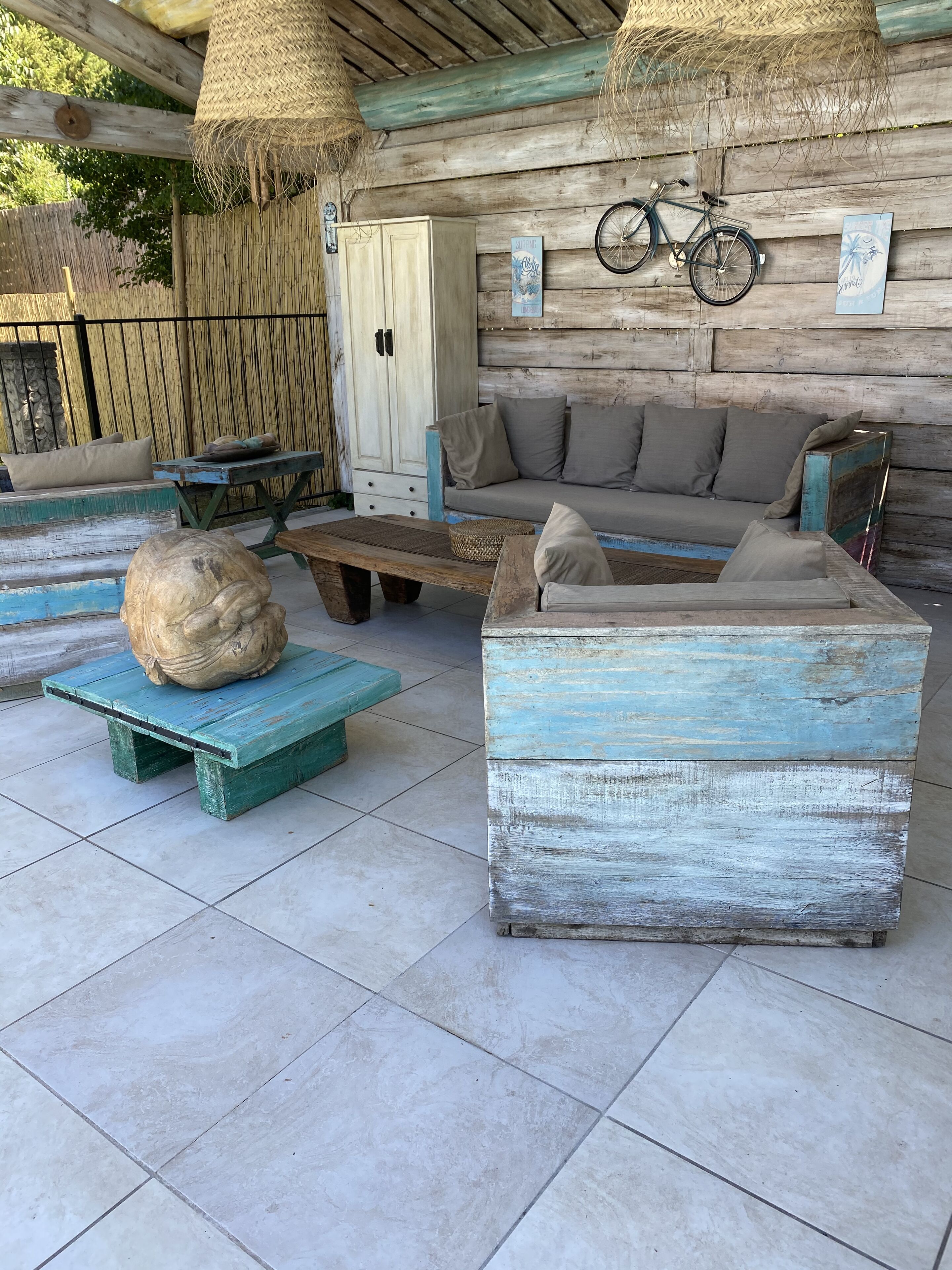 A rustic outdoor seating area with a wooden bench, a sofa, and a table.