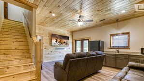 A wooden interior with a sofa, a television, and a kitchen area. - Pigeon Forge Getaway, Hot Tub, Game Room, Wifi, $560 FREE tickets each paid day! (Pigeon Forge)