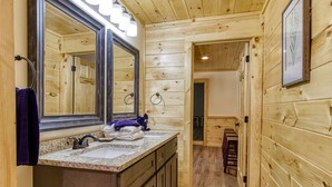 Ein Badezimmer im Holzblockhaus-Stil mit großem Spiegel, Waschbecken und Holzschränken.