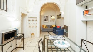 Um espaço de estar compacto com cozinha compacta, área de refeições e sala com sofá e poltronas.