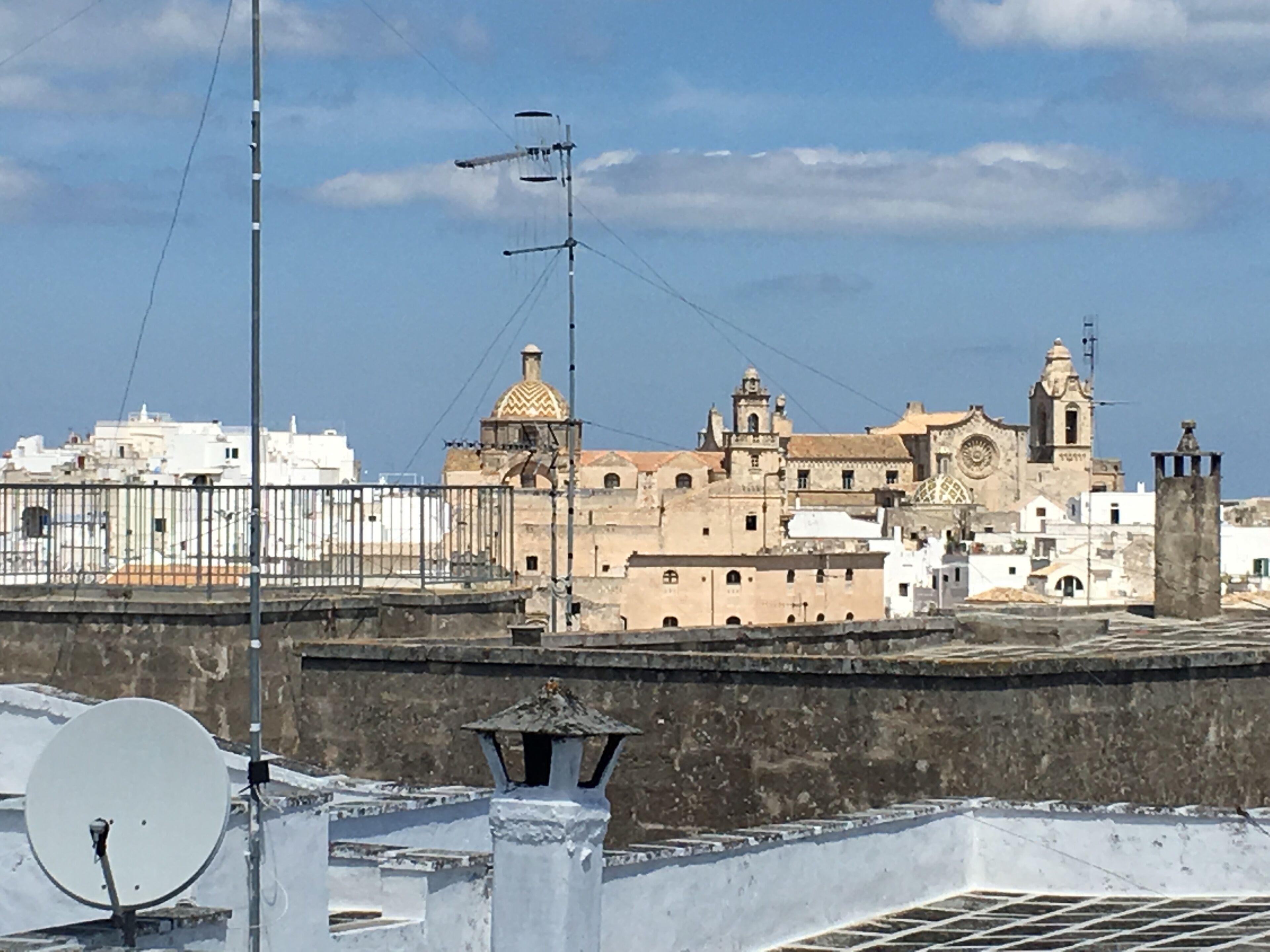 Un edificio histórico con una destacada torre de campanas y una cúpula, rodeado de edificios blancos.
