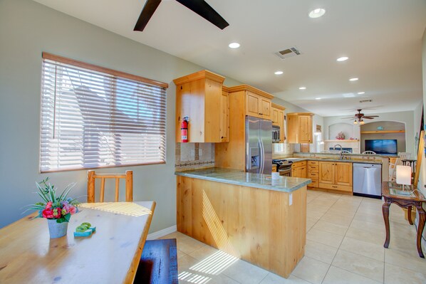 A kitchen with wooden cabinets, a central island, and a dining area with a table and chairs.