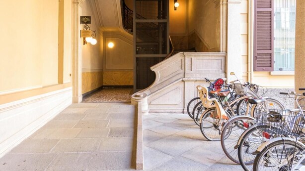 En hall med en trappa, ett cykelställ med flera cyklar och en skylt som visar vägen till en restaurang.