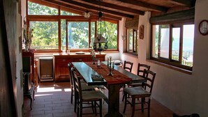 Un espace repas avec une table en bois, des chaises et une vue dégagée grâce à de grandes fenêtres.