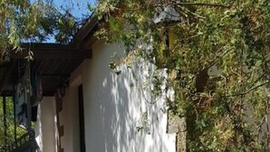 Un escalier avec des marches en bois et une rampe en métal, menant à un bâtiment à l’extérieur blanc et doté d’un mur en pierre d’un côté.