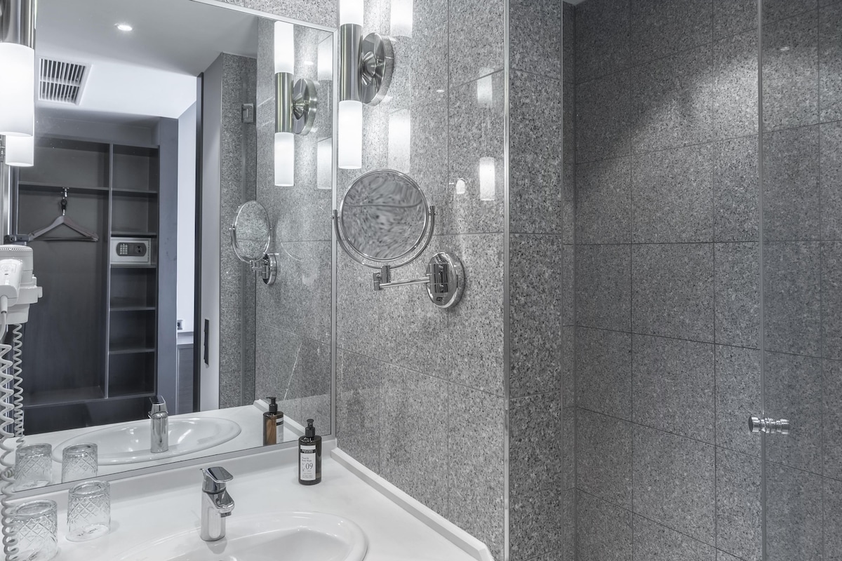 A modern bathroom with a double sink, a large mirror, and a glass shower enclosure.