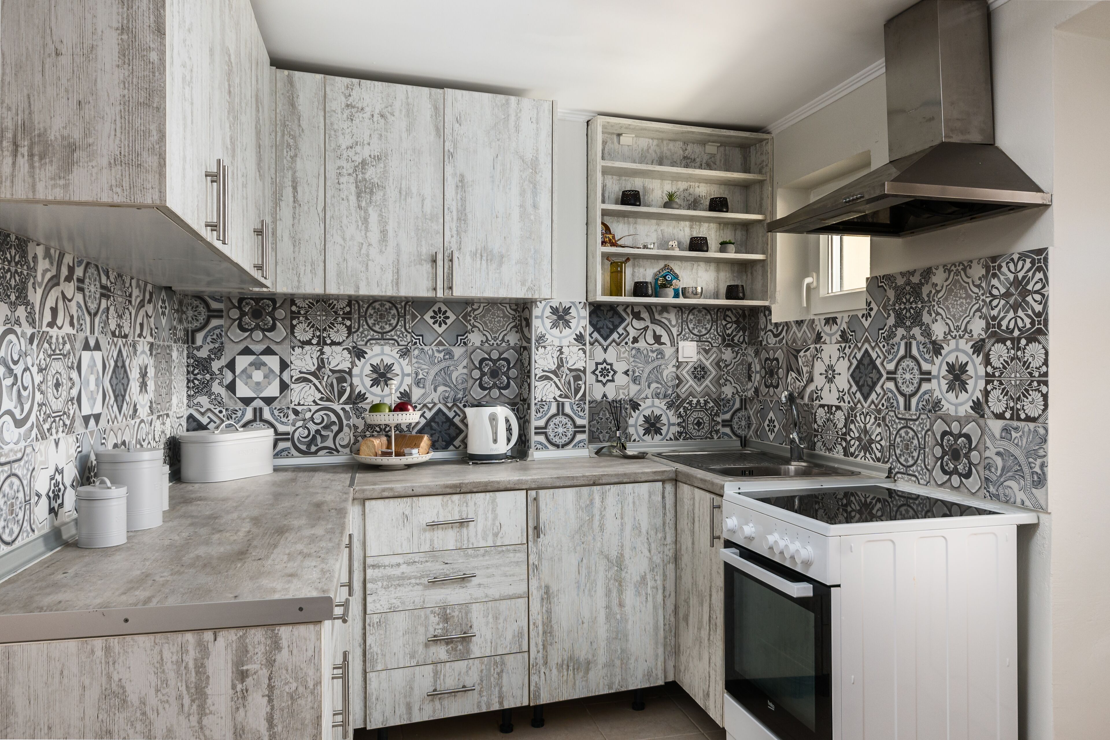 A kitchen with white cabinets, a built-in oven, and patterned backsplash tiles.