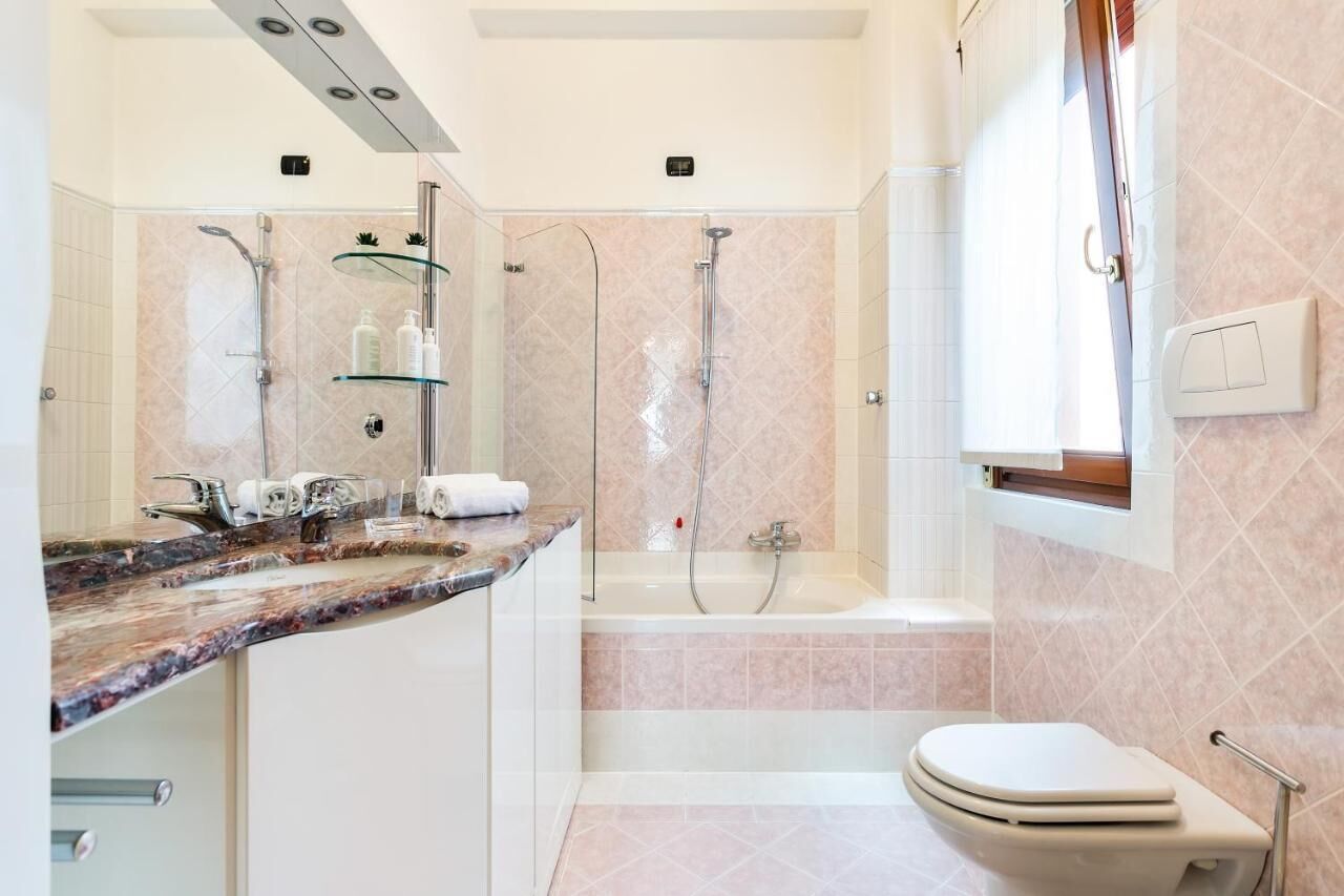 A modern bathroom with a marble countertop, a bathtub, and a toilet.