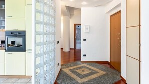 A hallway with a kitchen area on the left, a patterned wall, and a wooden door on the right. - MyHomeInComo - Santa Chiara Apartment (Como)