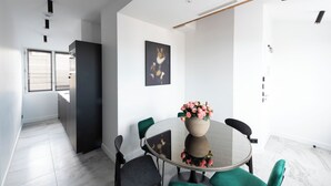 A modern dining area with a round glass table, green chairs, and a vase of flowers. - Seaham, 4 stars, View on Eiffel Tower and Sacré-Coeur (París)