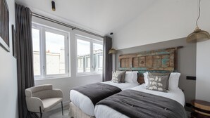 A bedroom with two beds, a chair, a large window, and a rustic headboard. - Seaham, 4 stars, View on Eiffel Tower and Sacré-Coeur (París)