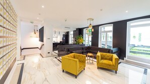 A modern lobby with a marble floor, yellow armchairs, a reception desk, and large windows. - Seaham, 4 stars, View on Eiffel Tower and Sacré-Coeur (París)