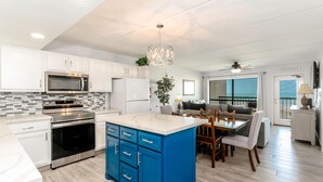 A modern kitchen with white cabinets, stainless steel appliances, and a blue island.