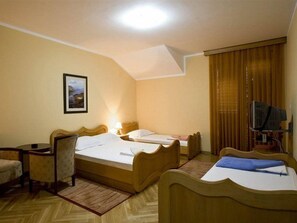 Ein Hotelzimmer mit zwei Betten, einem Schreibtisch, einem Sessel, einem Fernseher und einem Bild an der Wand.