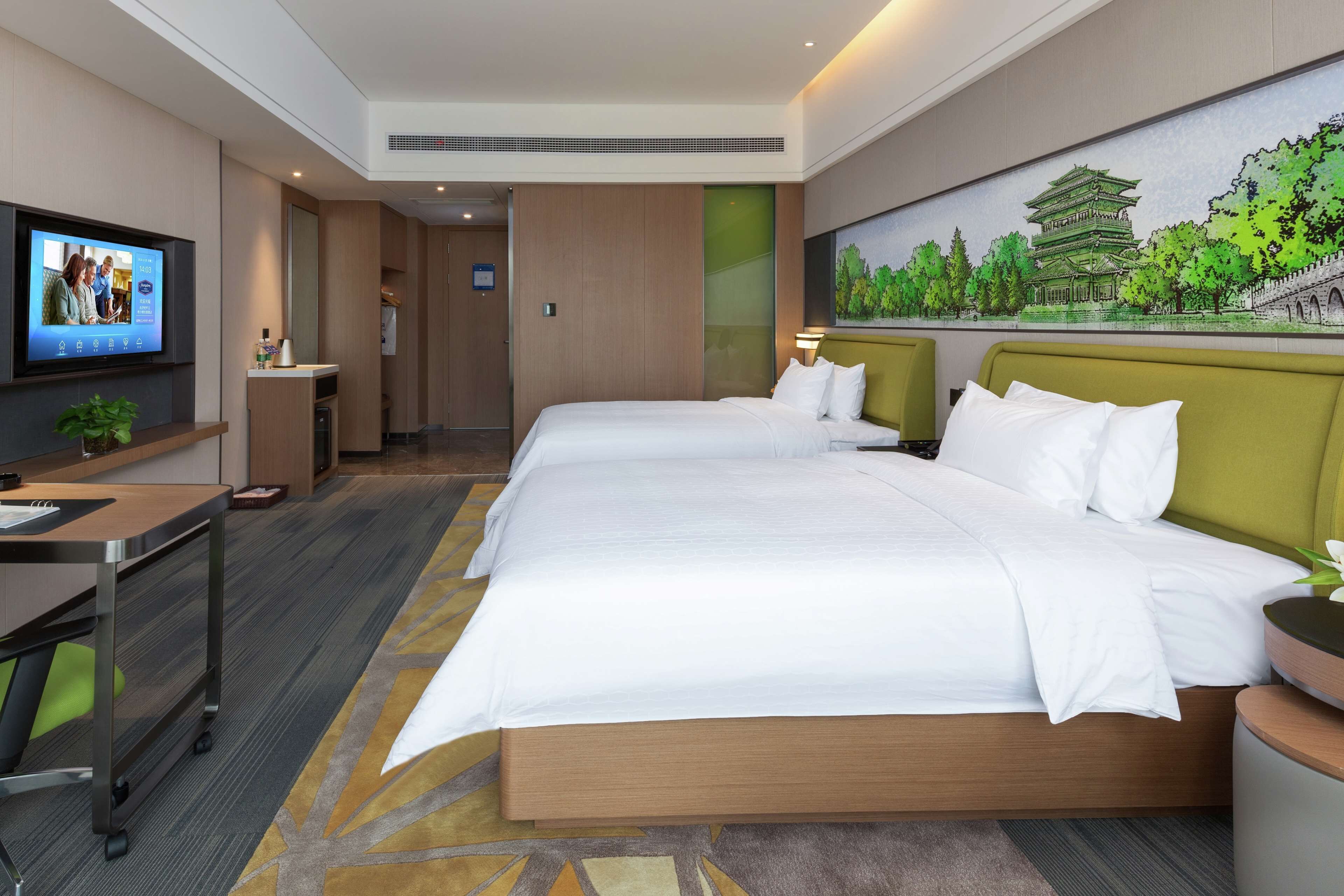 Une chambre d’hôtel avec un grand lit, un bureau, une télévision et un tableau représentant un bâtiment traditionnel.