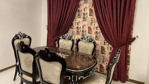 Un coin repas avec une table ronde, quatre chaises et des rideaux rouges.