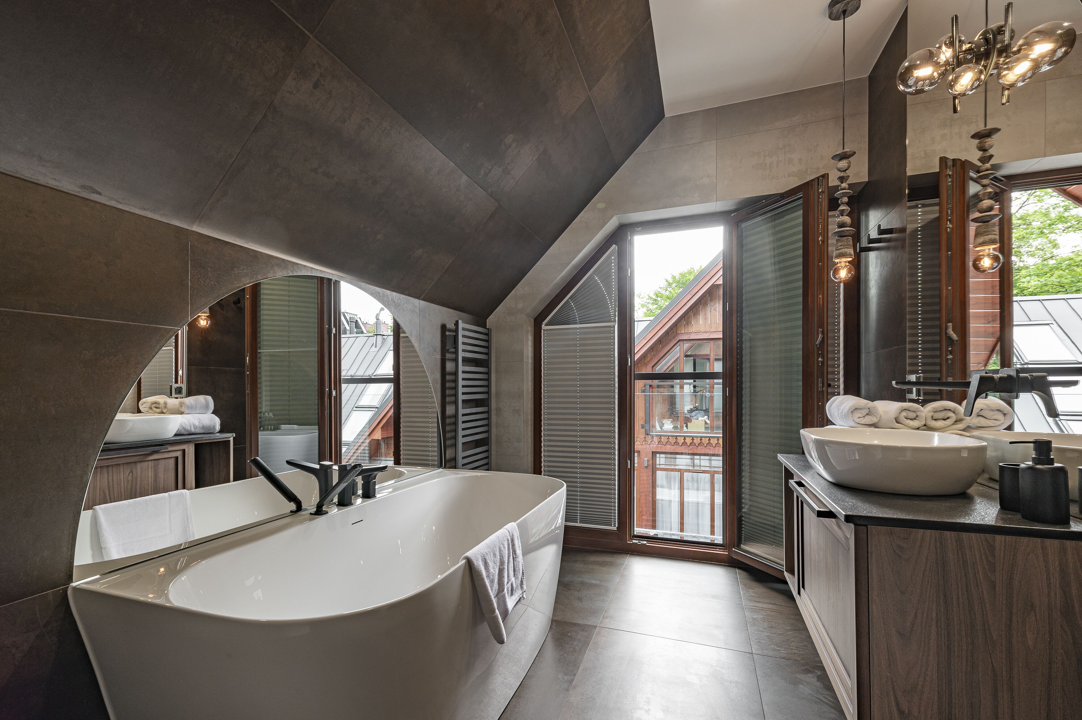 A modern bathroom with a freestanding bathtub, dual sinks, and a large window providing natural light.