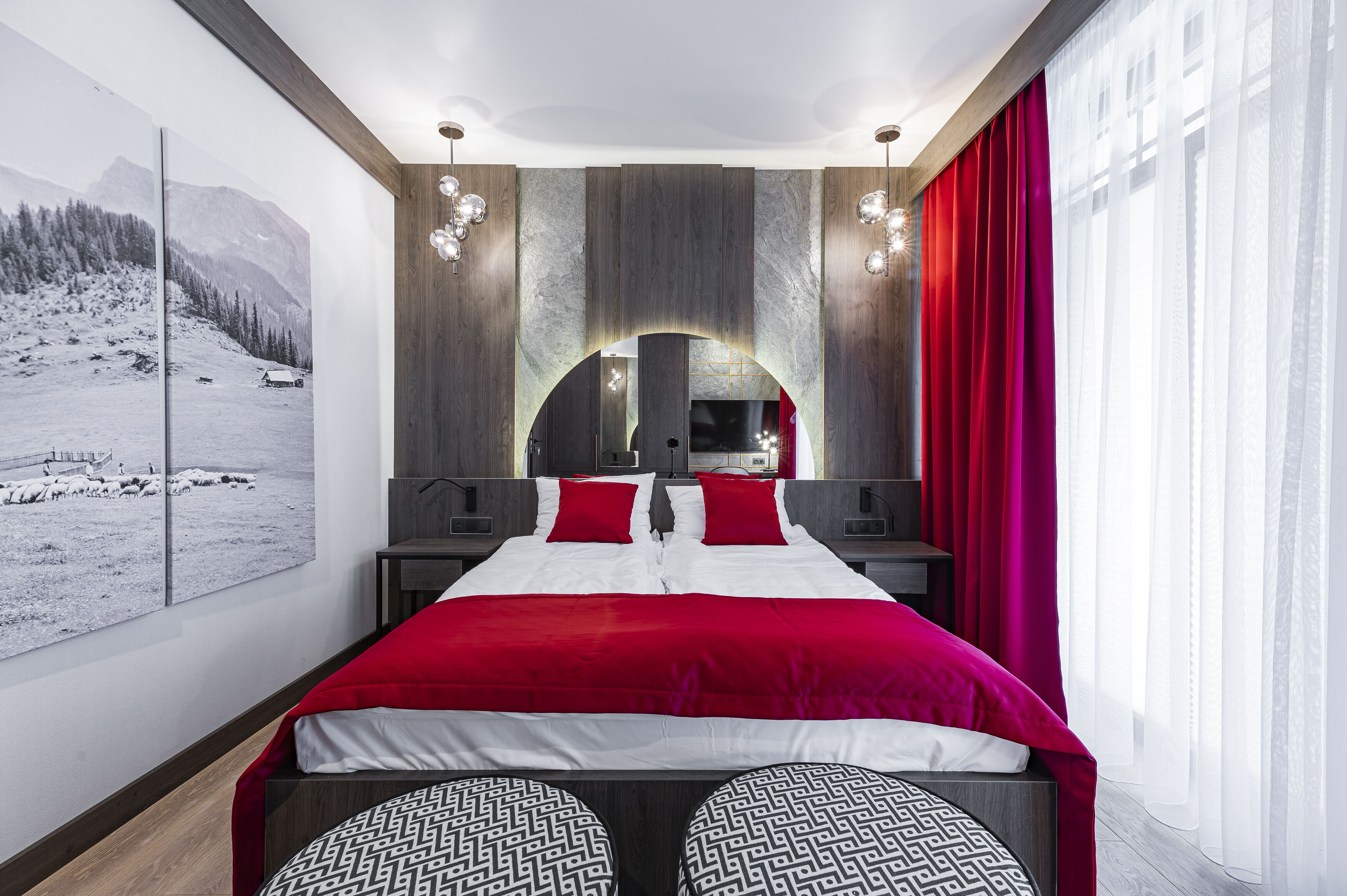 A modern bedroom with a large bed, a mirror, and a view of a snowy landscape.