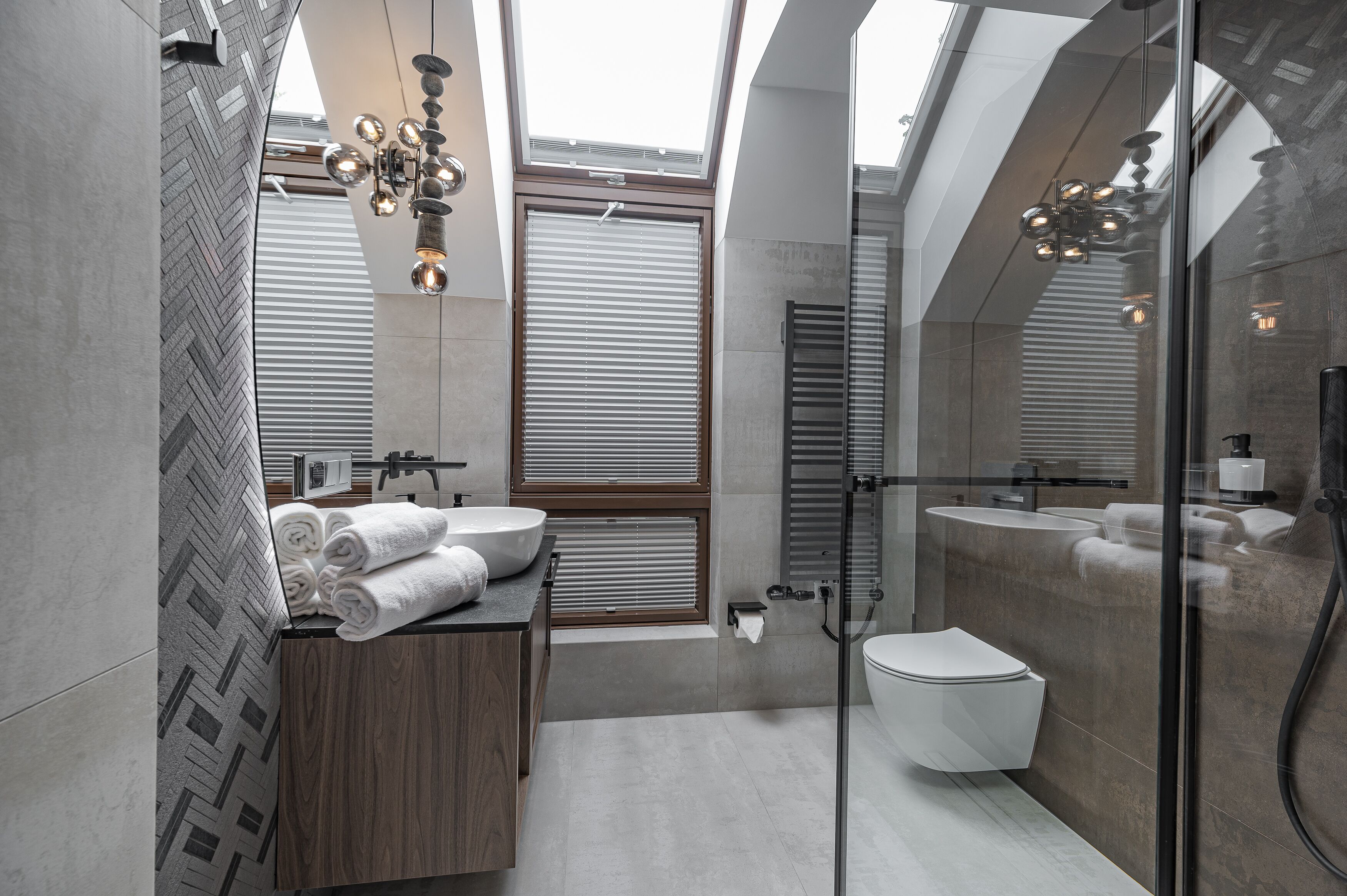Un baño moderno con tragaluz, tocador de madera, cabina de ducha de vidrio y retrete.