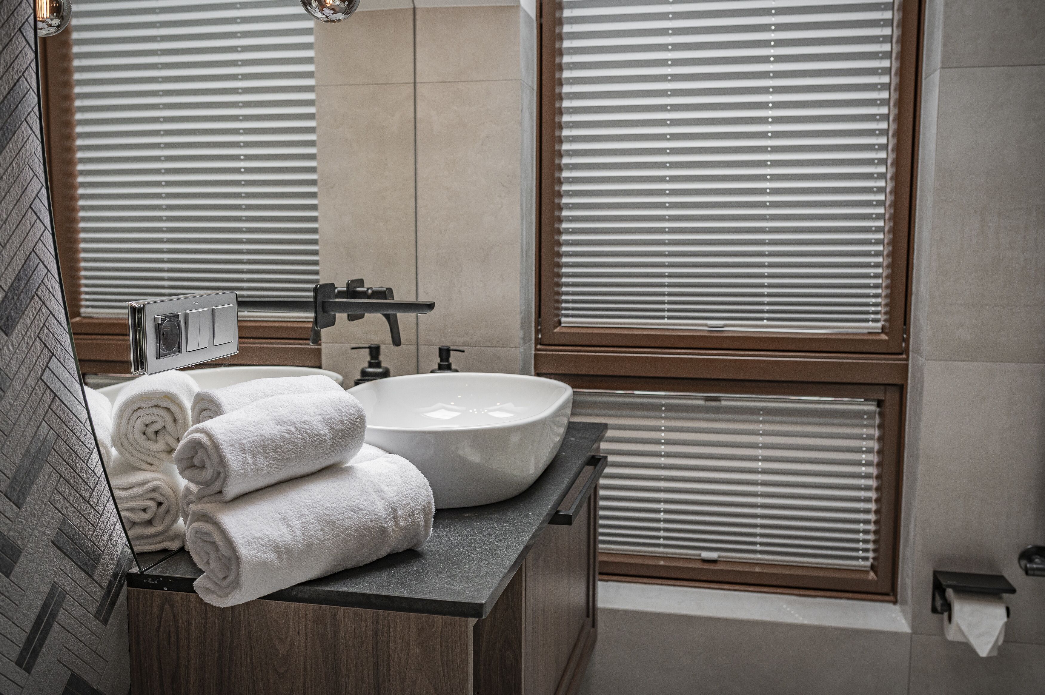 A modern bathroom with a large sink, wooden vanity, and a mirror.