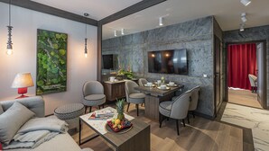 Una sala de estar moderna con comedor, un televisor de pantalla plana en la pared y una cortina roja al fondo.
