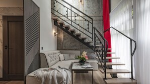 Una sala de estar moderna con un sofá, una mesa de centro y una escalera con una cortina roja.