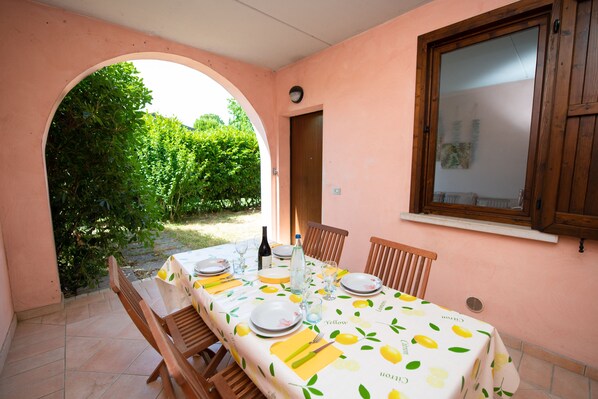 Un coin repas avec une table dressée pour quatre personnes, une fenêtre et une arche donnant sur un jardin.