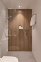Un baño moderno con tocador de madera, ducha con cabezal de ducha manual y perchero para toallas.