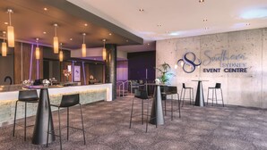 Un centro de eventos moderno con área de bar, disposición de asientos y un cartel llamativo.