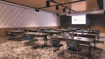 A conference room with tables, chairs, and a projector screen displaying the Sydney Event Centre logo.