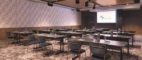 A conference room with tables, chairs, and a projector screen displaying the Sydney Event Centre logo.
