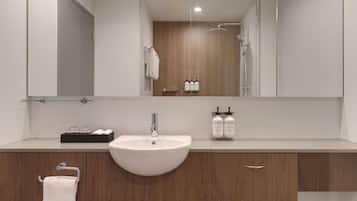 A modern bathroom with a white sink, wooden vanity, and a large mirror.