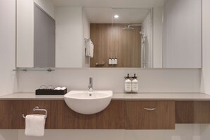 Une salle de bain moderne avec un lavabo blanc, un meuble-lavabo en bois et un grand miroir.