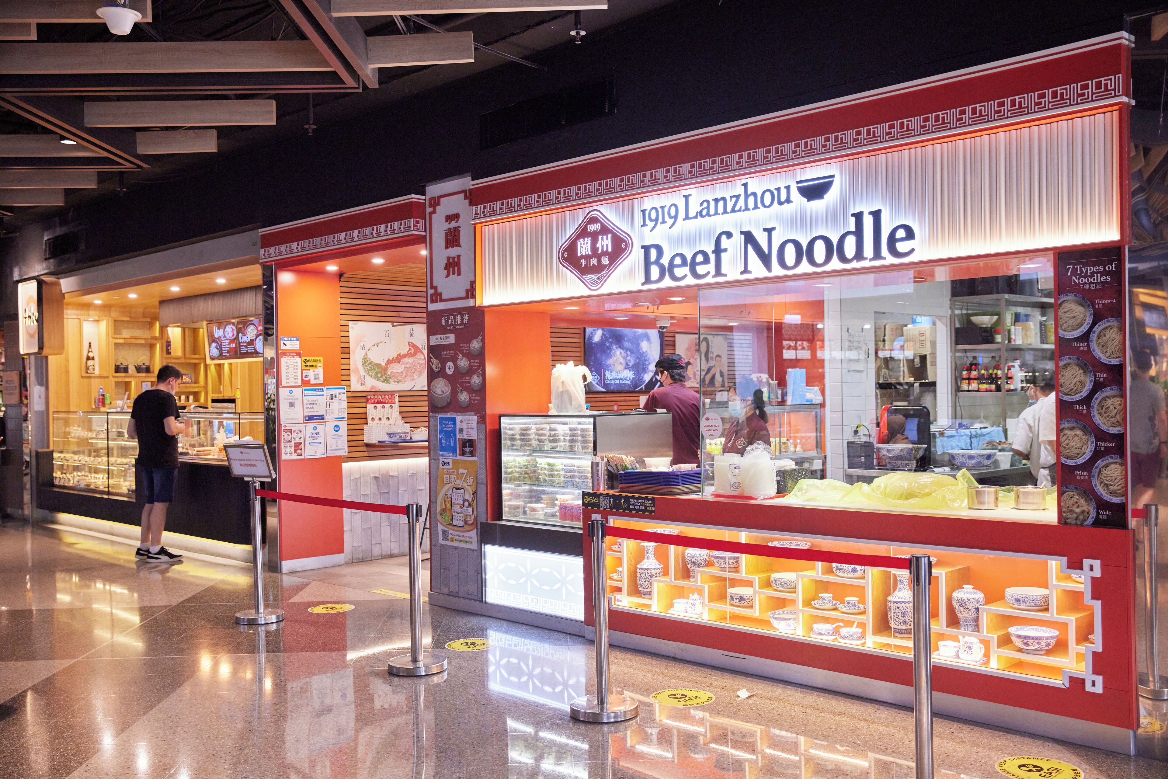 Un restaurante llamado 1919 Lanzhou Beef Noodle con una exhibición de tazones y utensilios.