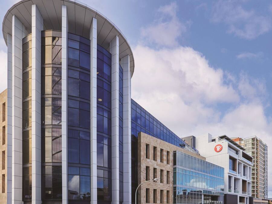 Un edificio moderno con una facciata in vetro curvo e un tetto piatto.