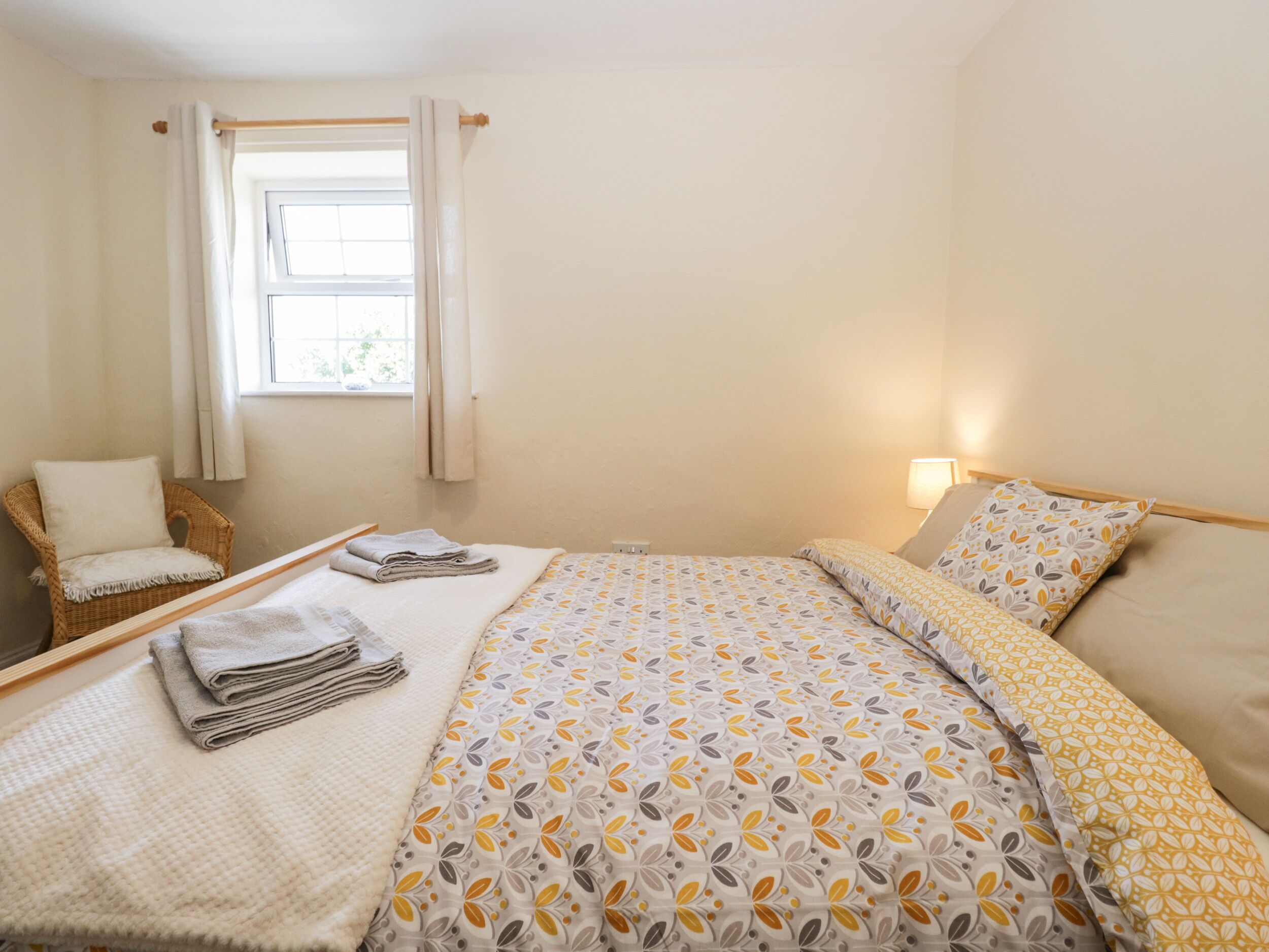 A bedroom with a bed, a chair, and a window.