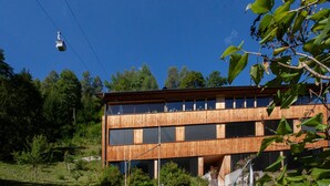 A modern building with a wooden facade, large windows, and a cable car in the background.