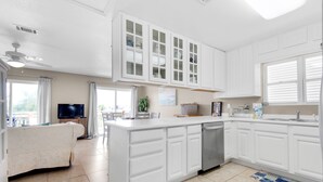A modern kitchen with white cabinetry, a built-in dishwasher, and a large island with a sink. - 🌴Walk2Beach-Outdoor Patio-3BR Moon Tide Cottage🌴 (Pensacola Beach)
