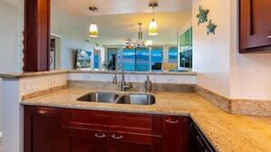 A kitchen with granite countertops, a double sink, and wooden cabinets.
