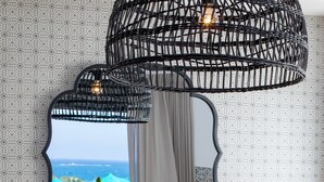 A dining area with a wooden table, a potted cactus, and a mirror reflecting a view of the ocean. - AmazingApartment W Views of Achziv Beach (Nahariya)