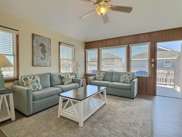 A spacious living room with two grey sofas, a coffee table, and a ceiling fan.