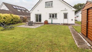 A two-story house with a white exterior, a front door, and a small patio with a table and chairs. - 17 Clover Hill (Killorglin)