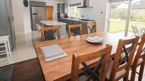 A modern kitchen with grey cabinets, a wooden dining table, and a view of the backyard. - 17 Clover Hill (Killorglin)