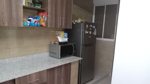 A kitchen with wooden cabinets, a microwave, and a refrigerator. - perfect apartment (Nairobi)