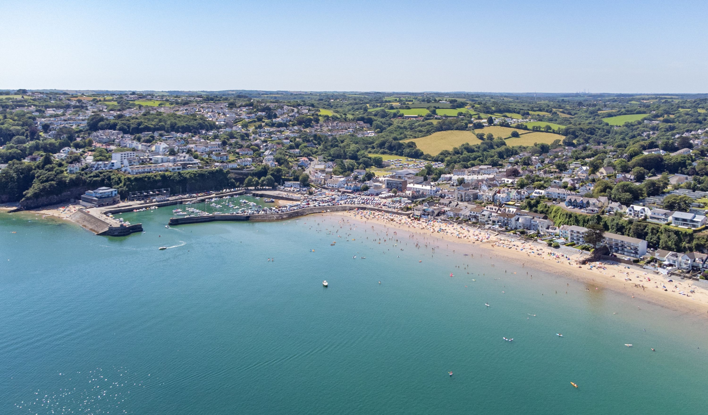 An aerial view of a coastal town with a marina, beach, and residential areas.