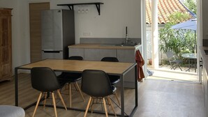 Uma cozinha moderna com frigorífico embutido, vigas de madeira no teto e um espaço de refeições com mesa e cadeiras.