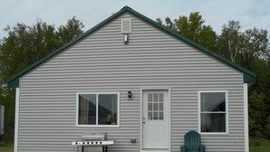 A small, single-story house with a green roof, a front door, and a window on each side. - Post and beam cabin with queen size  and bunk (Shirley Mills)