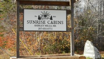Een houten bordje voor Sunrise Cabins met contactgegevens en het jaar van oprichting.